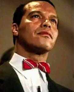 A young Minister Louis Farrakhan wearing a red and white striped bowtie, captured in a poised and confident moment.