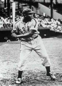 Young Josh Gibson in a Homestead Grays uniform during the early 1930s, captured mid-batting stance in a Negro League baseball game.